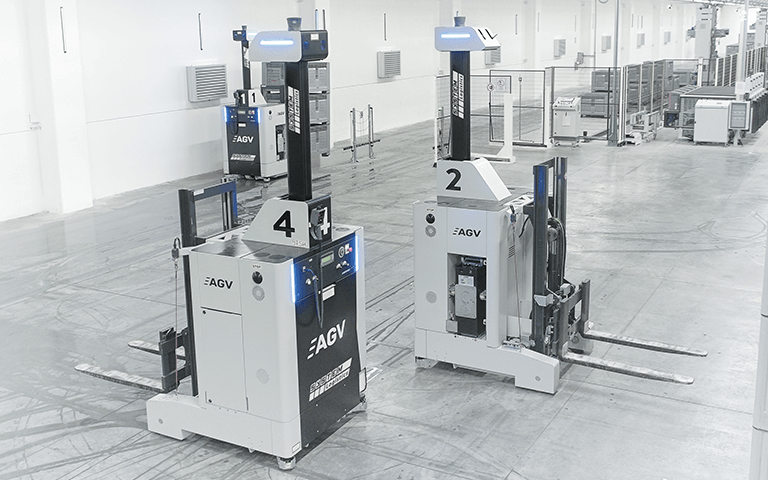 Zwei Gabelstapler FTS/ AGV's nebeneinander in einer Halle