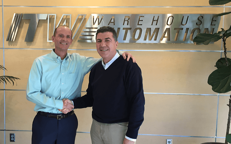 Zwei Menschen geben sich die Hand, im Hintergrund der Schriftzug der Firma ITW Warehouse Automation