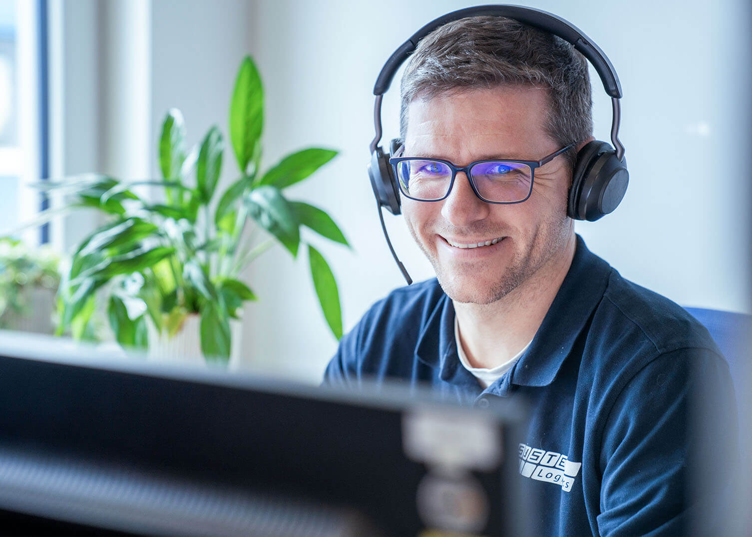 Mitarbeiter von System Logistics mit Headset vor Computer bereit f&uuml;r Besprechungen