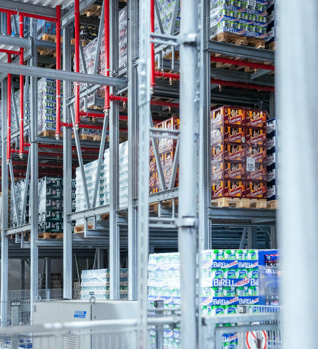 Fully loaded pallets stacked on top of each other in a high-bay warehouse from System Logistics